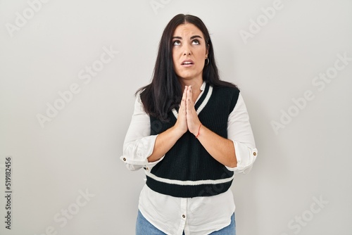 Young hispanic woman standing over isolated background begging and praying with hands together with hope expression on face very emotional and worried. begging.