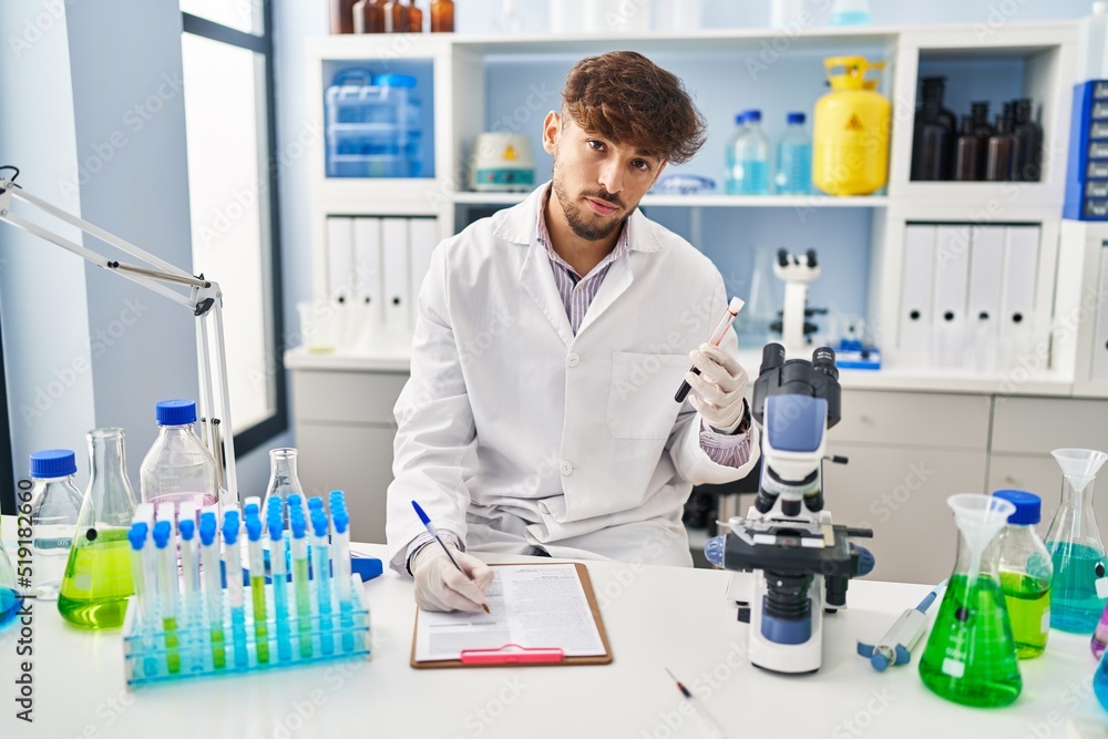 Young arab man scientist write on document analysing blood test tube at laboratory Young arab man scientist write on document analysing blood test tube at laboratory
