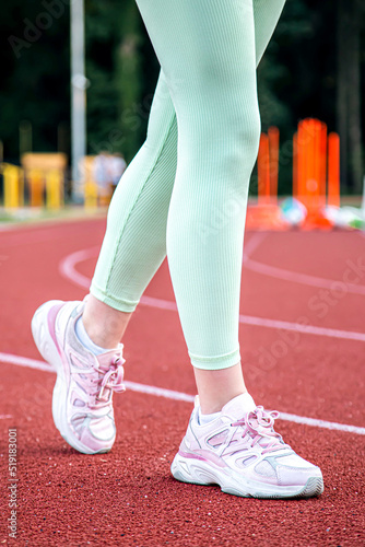 Close-up, female legs in sneakers at the stadium.