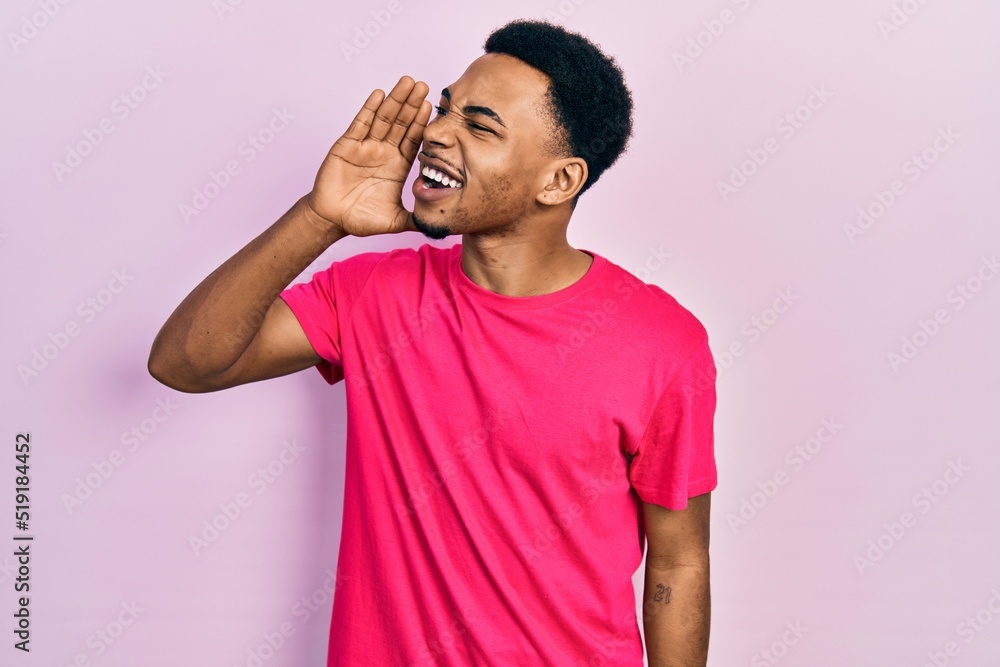 Young african american man wearing casua t shirt shouting and screaming loud to side with hand on mouth. communication concept. Young african american man wearing casua t shirt shouting and screaming loud to side with hand on mouth. communication concept.