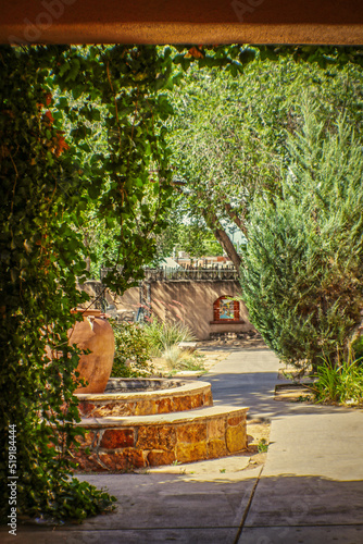 Rustic Santa Fe courtyard with fountain framed by adobe doorway with vines photo