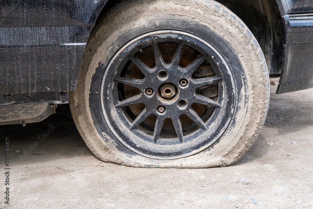 Close-up Of A Damaged Flat Tire Of A Car On The Road. Old wheel car dirty and flat tires. Punctured wheel of a modern car on the road. Car tire puncture.