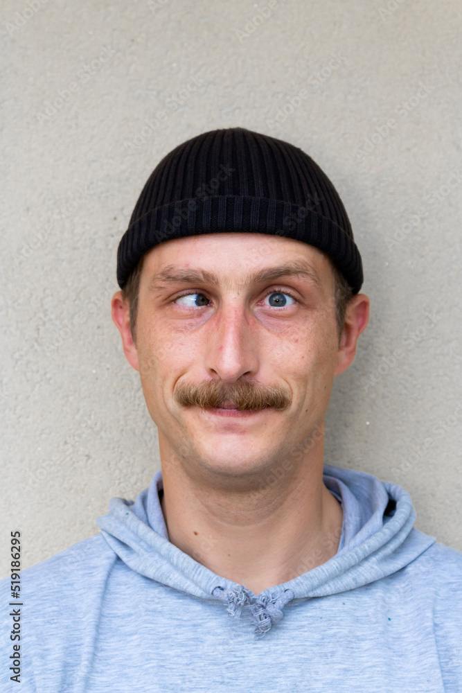 Portrait of young funny man with crossed eyes isolated on gray background
