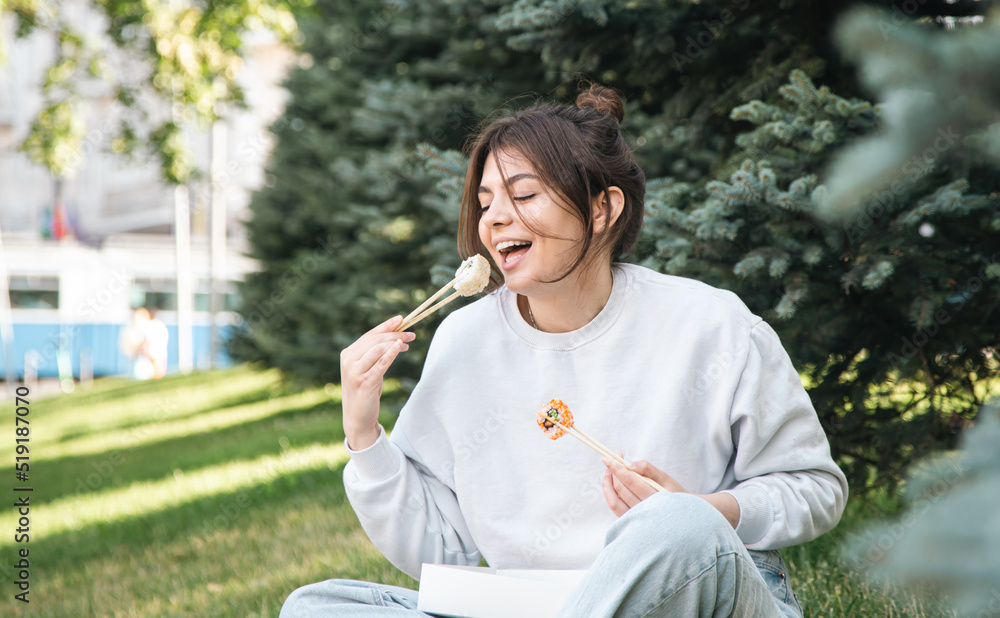 A young woman eating sushi in the park, picnic in nature. A young woman eating sushi in the park, picnic in nature.