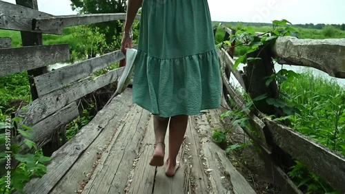 Women's legs go along the old wooden bridge. Close-up
