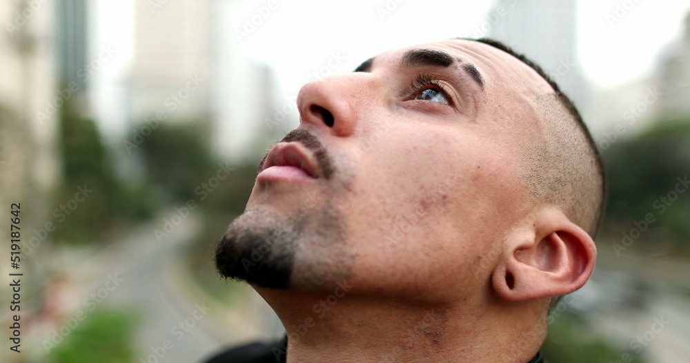 Obraz premium Hispanic man closing eyes looking to sky with hope and faith