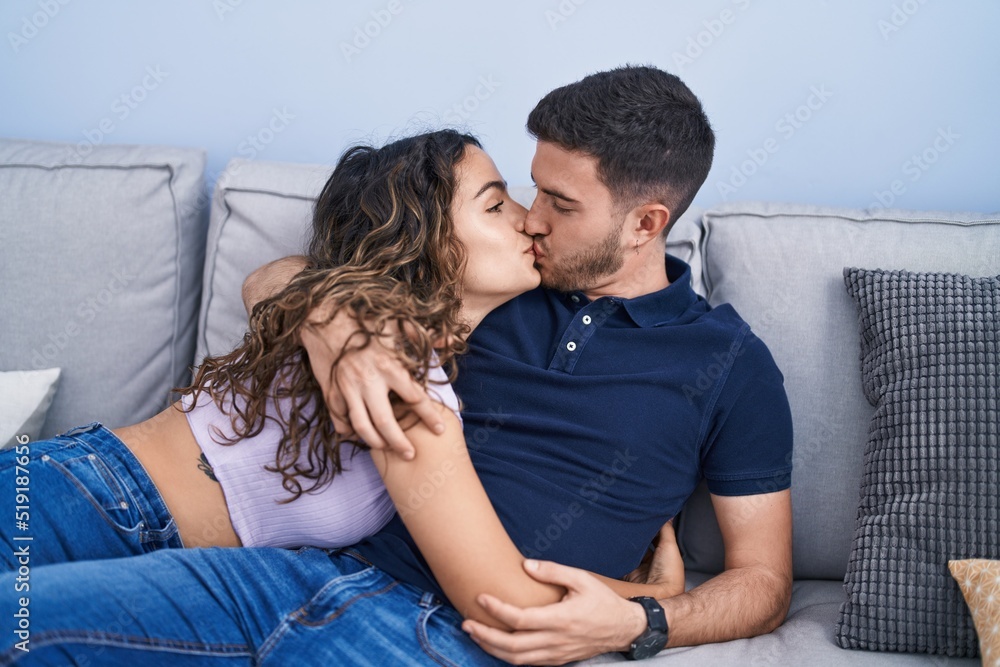 Young hispanic couple lying on sofa hugging each other and kissing at home Young hispanic couple lying on sofa hugging each other and kissing at home