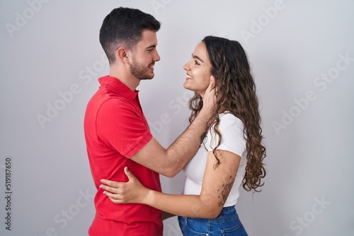 Young hispanic couple standing over isolated background looking to side, relax profile pose with natural face and confident smile.