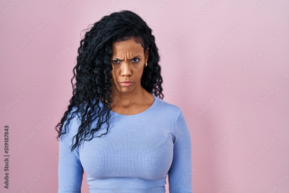 Middle age hispanic woman standing over pink background skeptic and nervous, frowning upset because of problem. negative person. Middle age hispanic woman standing over pink background skeptic and nervous, frowning upset because of problem. negative person.