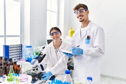 Man and woman partners wearing scientist uniform working at laboratory
