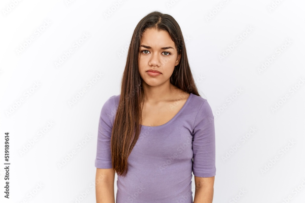 Young brunette woman standing by isolated background relaxed with serious expression on face. simple and natural looking at the camera. Young brunette woman standing by isolated background relaxed with serious expression on face. simple and natural looking at the camera.