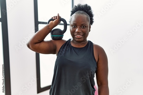 Quadro su tela Young african american woman smiling confident training using dumbbell at sport