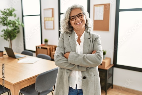 Photography Middle age grey-haired businesswoman smiling happy standing with arms crossed gesture at the office