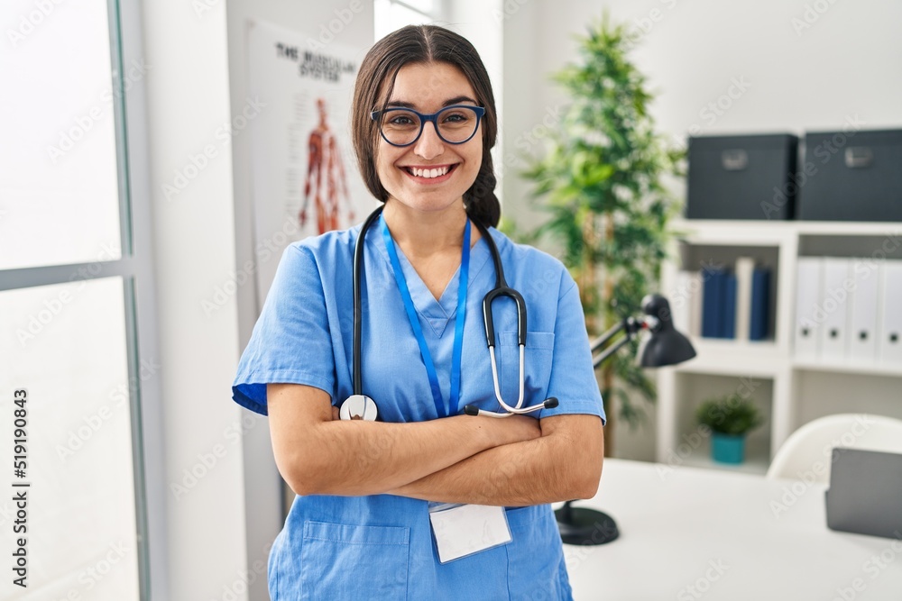 Young hispanic woman wearing doctor uniform standing with arms crossed gesture at clinic Young hispanic woman wearing doctor uniform standing with arms crossed gesture at clinic