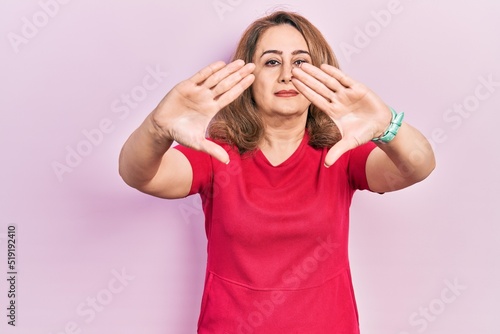 Middle age caucasian woman wearing casual clothes doing frame using hands palms and fingers, camera perspective © Krakenimages.com