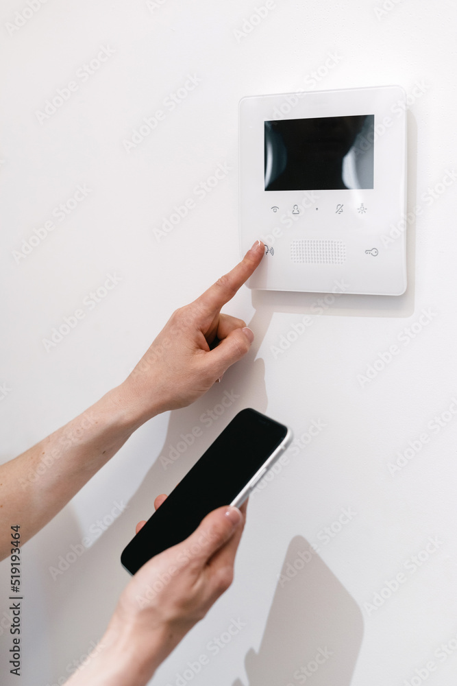 Woman using smartphone, controlling temperature on digital panel