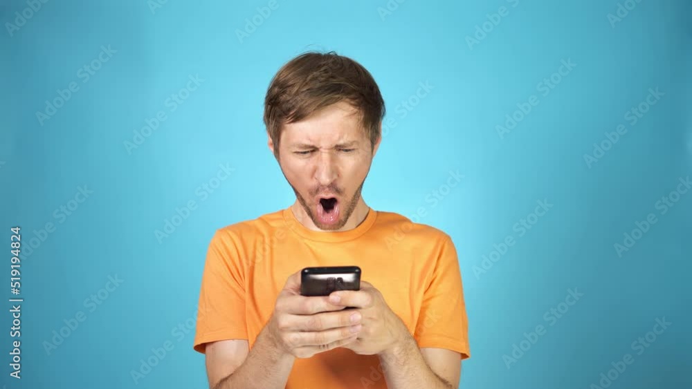 Confused young man with disgust look at smartphone screen in surprise. Grimacing guy reading a text message. Confused young man with disgust look at smartphone screen in surprise. Grimacing guy reading a text message.