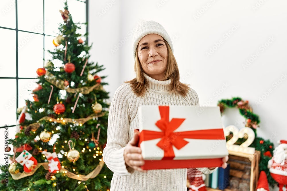 Middle age caucasian woman smiling confident unboxing christmas gift at home Middle age caucasian woman smiling confident unboxing christmas gift at home
