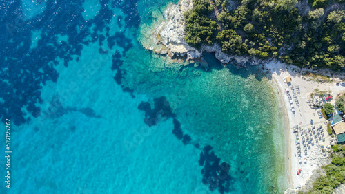 View from above  aerial view of an emerald and transparent Mediterranean sea with a white beach full of colored beach umbrellas and tourists who relax and swim