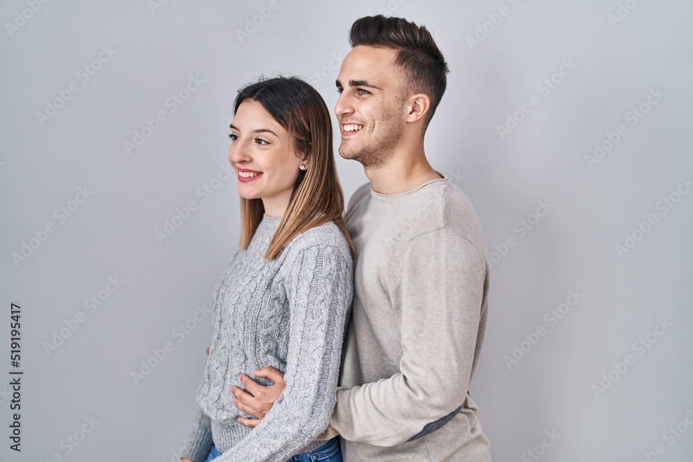 Young hispanic couple standing over white background looking to side, relax profile pose with natural face and confident smile. Young hispanic couple standing over white background looking to side, relax profile pose with natural face and confident smile.