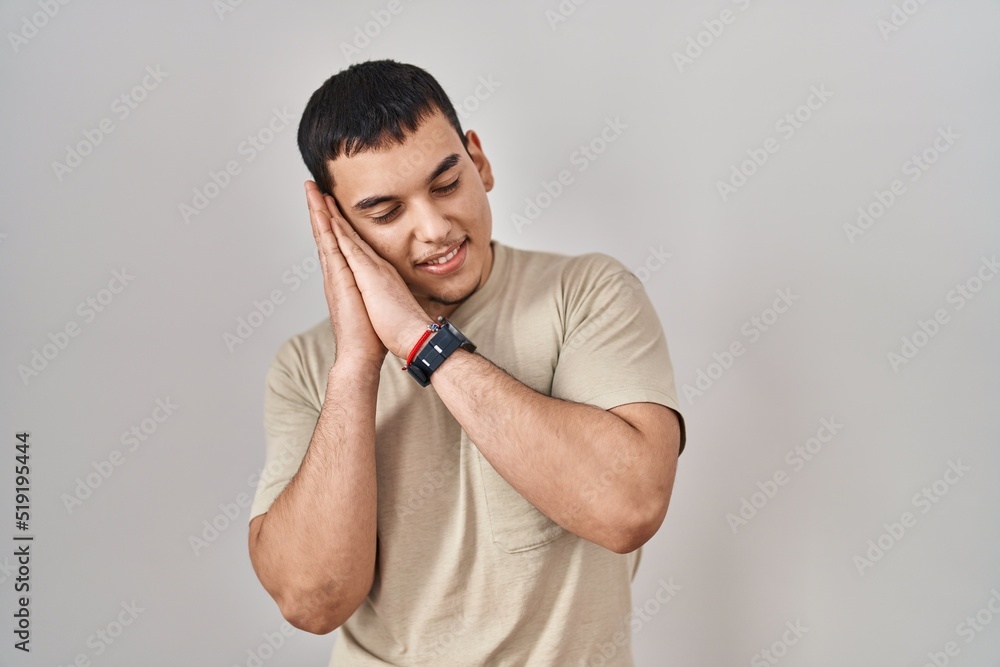 Young arab man wearing casual t shirt sleeping tired dreaming and posing with hands together while smiling with closed eyes. Young arab man wearing casual t shirt sleeping tired dreaming and posing with hands together while smiling with closed eyes.