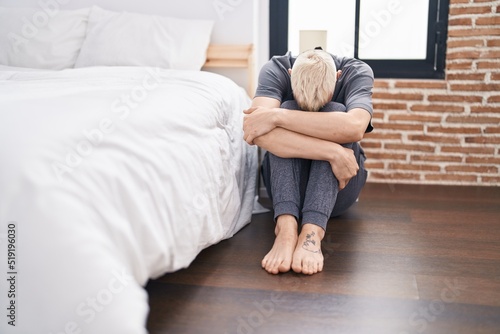 Young caucasian man stressed sitting on floor at bedroom