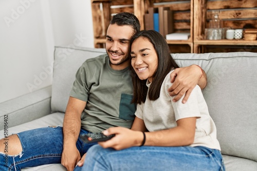 Young latin couple smiling happy watching tv at home.