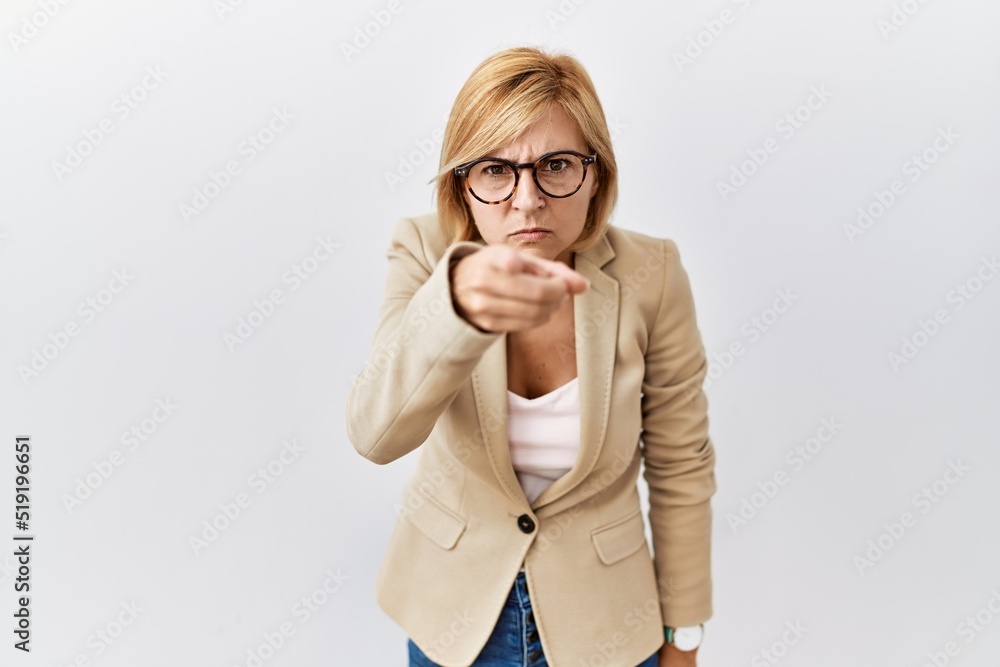 Middle age blonde business woman standing over isolated background pointing displeased and frustrated to the camera, angry and furious with you