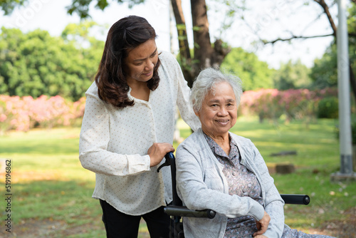 Caregiver help and care Asian senior or elderly old lady woman patient sitting and happy on wheelchair in park, healthy strong medical concept.