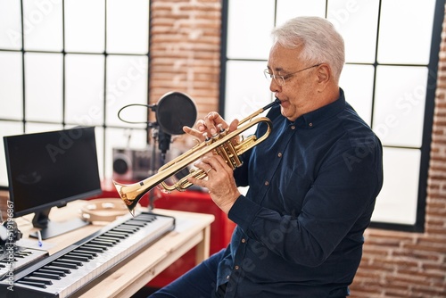 Senior man musician playing trumpet at music studio