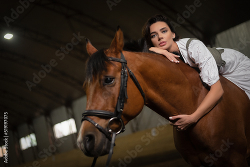 Young beautiful girl with the horse in the stable. © Dmitriy