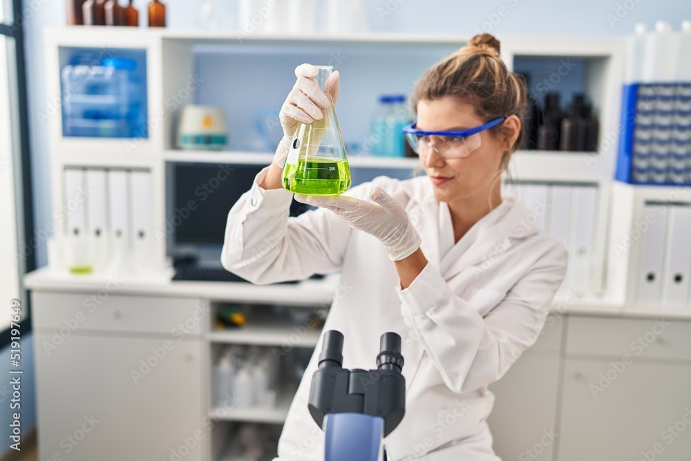 Young blonde woman wearing scientist uniform looking liquid on test tube at laboratory Young blonde woman wearing scientist uniform looking liquid on test tube at laboratory