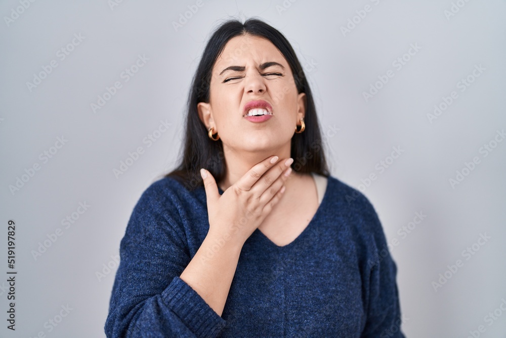 Young brunette woman standing over isolated background touching painful neck, sore throat for flu, clod and infection Young brunette woman standing over isolated background touching painful neck, sore throat for flu, clod and infection