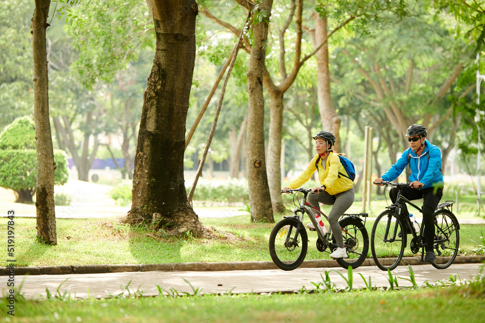 Couple enjoying bicycle ride in city park on sunny Sunday morning