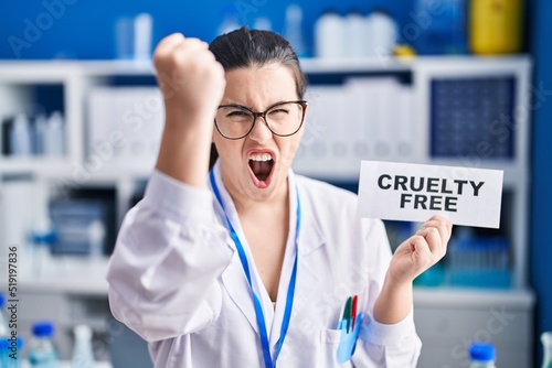 Young brunette woman working on cruelty free laboratory annoyed and frustrated shouting with anger, yelling crazy with anger and hand raised