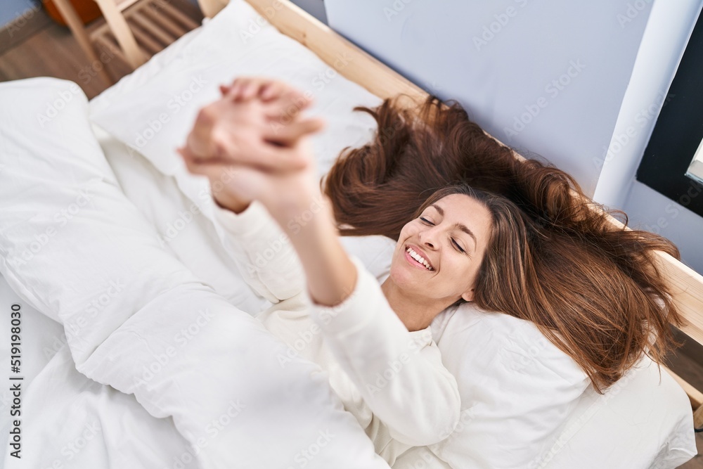 Young woman stretching arms lying on bed at bedroom Young woman stretching arms lying on bed at bedroom