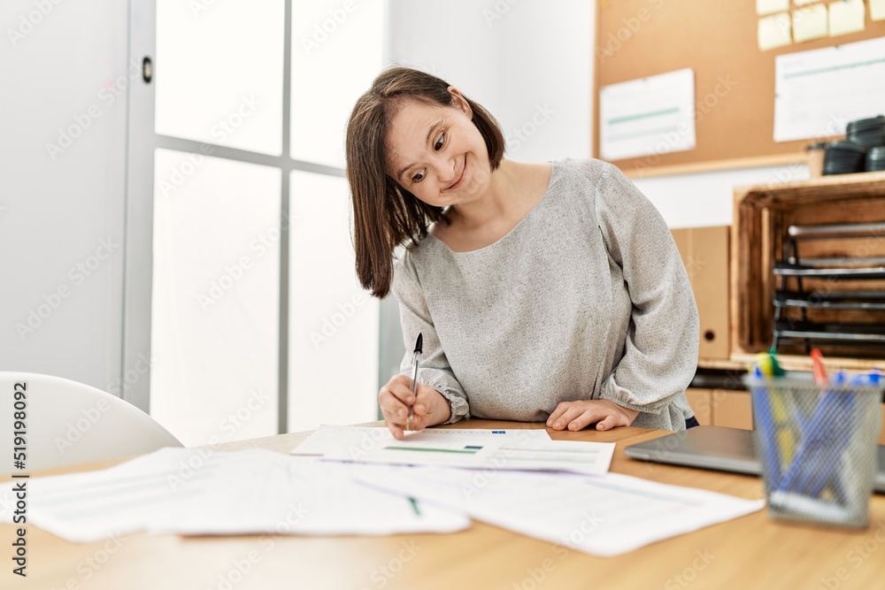 Brunette woman with down syndrome working with documents at business office Brunette woman with down syndrome working with documents at business office