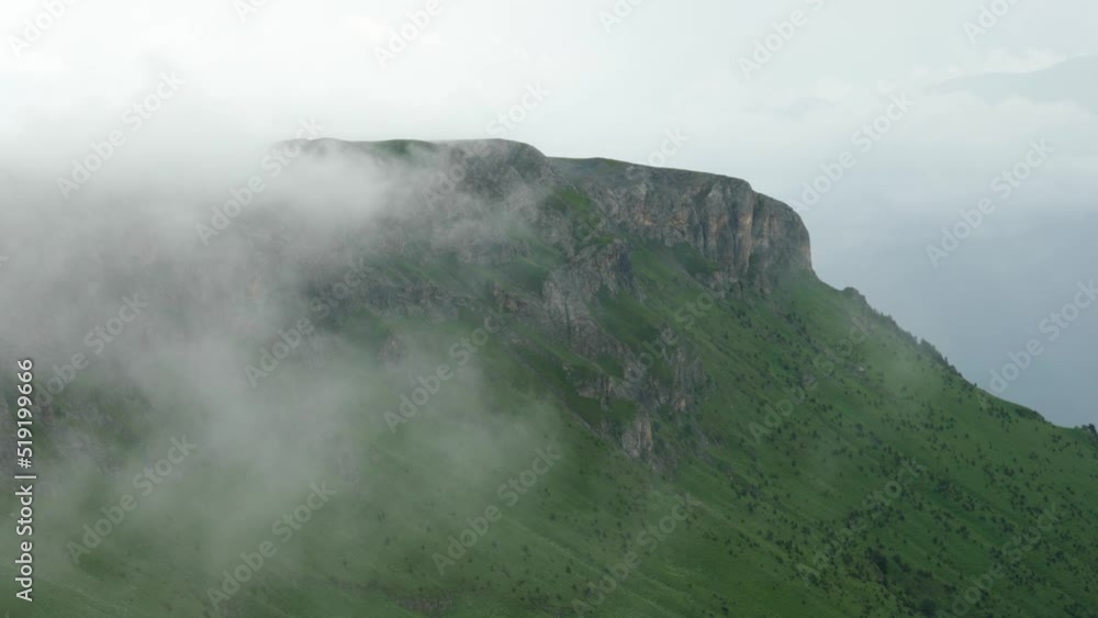 The rocky mountains are covered with clouds. Smooth movement of the camera. Rainy weather in the mountains. Aerial photography of mountain peaks on a foggy day. Travel and tourism The rocky mountains are covered with clouds. Smooth movement of the camera. Rainy weather in the mountains. Aerial photography of mountain peaks on a foggy day. Travel and tourism