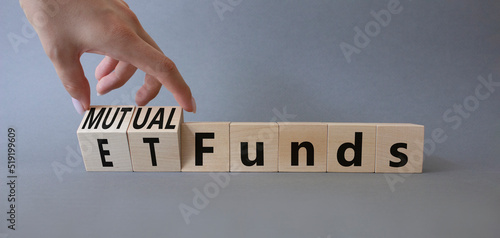 Mutual funds vs ETF symbol. Businessman hand turns a cube and changes words ETF 'Exchange-Traded Fund' to Mutual funds. Beautiful grey background. Business and ETF vs mutual funds concept. Copy space photo