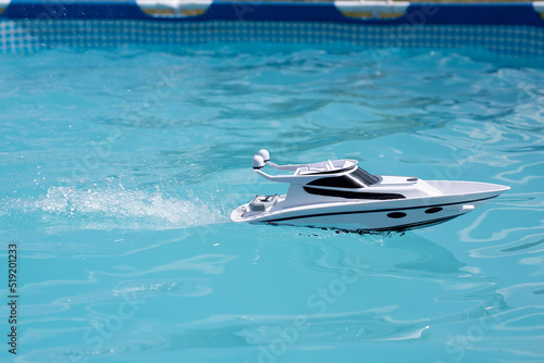 boat in the pool splashing water. children's toy on the radio control. summer games © Александр Ивчик