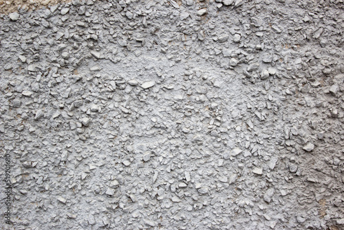 The texture of the concrete wall part with a small crumb of stone. Grey Textured cement wall background with a stone chip. Concrete wall of the building with stones of different sizes.