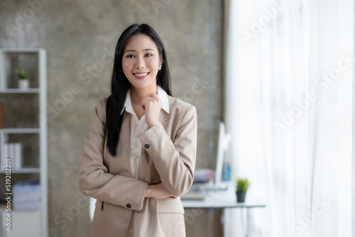 Beautiful Asian businesswoman standing with her arms crossed and confidently looking at the camera in the office.