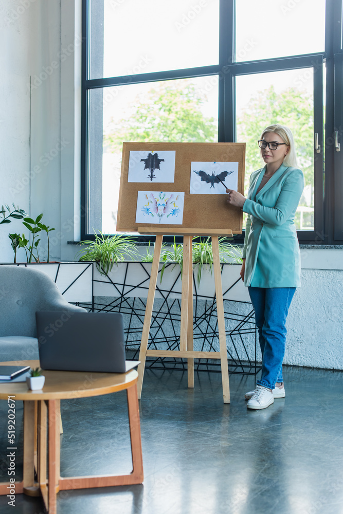Psychologist pointing at Rorschach test on board during video call on laptop in consultation room. Psychologist pointing at Rorschach test on board during video call on laptop in consultation room.