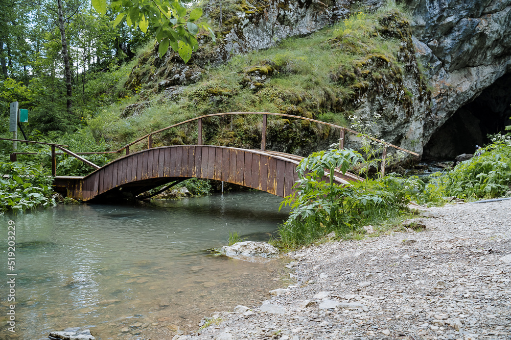 A wooden bridge is thrown over a mountain stream in the National Park of Bashkortostan, the Shulgantash Kapova Cave Reserve, the nature of Russia. A wooden bridge is thrown over a mountain stream in the National Park of Bashkortostan, the Shulgantash Kapova Cave Reserve, the nature of Russia.