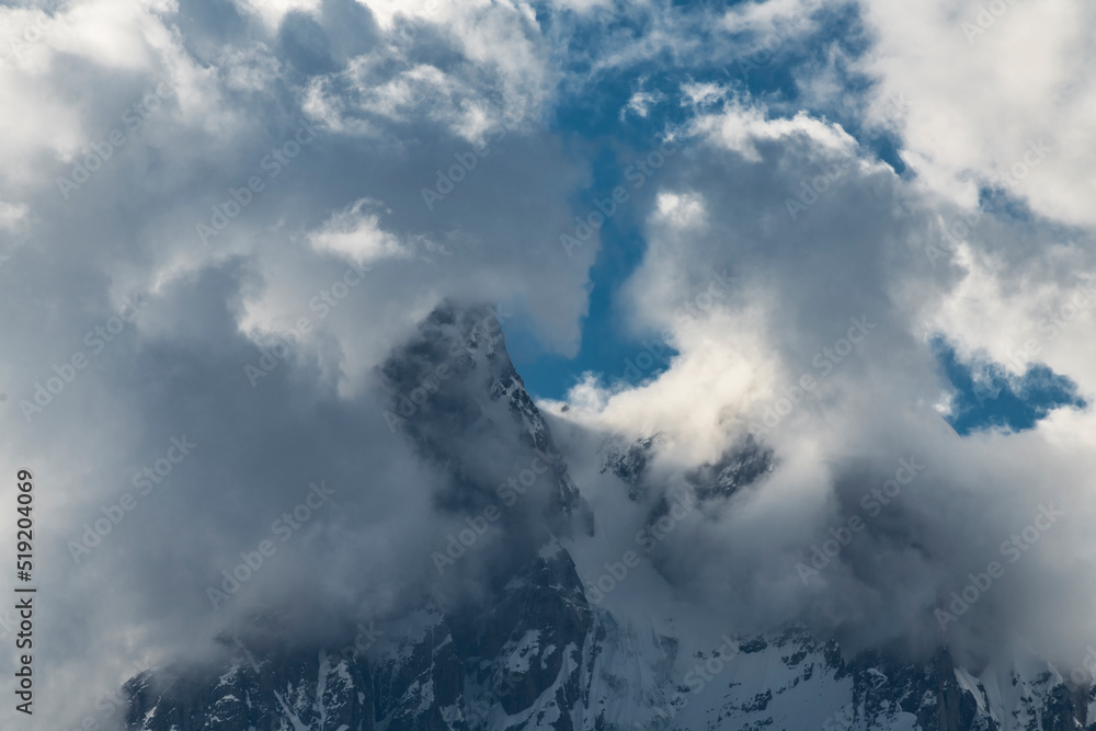 Clouds and fog over the snow covered mountains. High mountains peak, winter landscape.