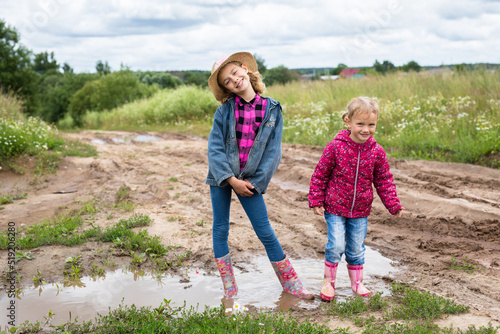 Two girls run through the puddles and play.