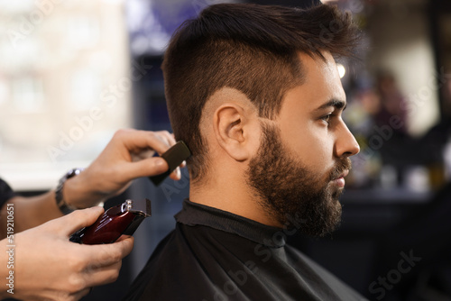 Professional hairdresser working with client in barbershop photo