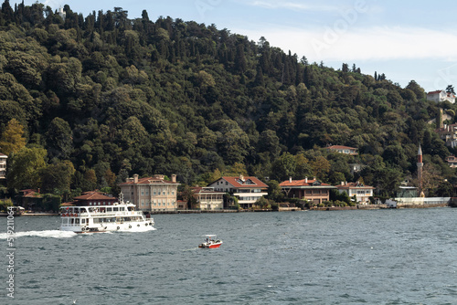 View of cruise tour boat on Bosphorus and historical and traditional mansions in Kandilli area of Asian side of Istanbul. It is a sunny summer day. Beautiful scene.