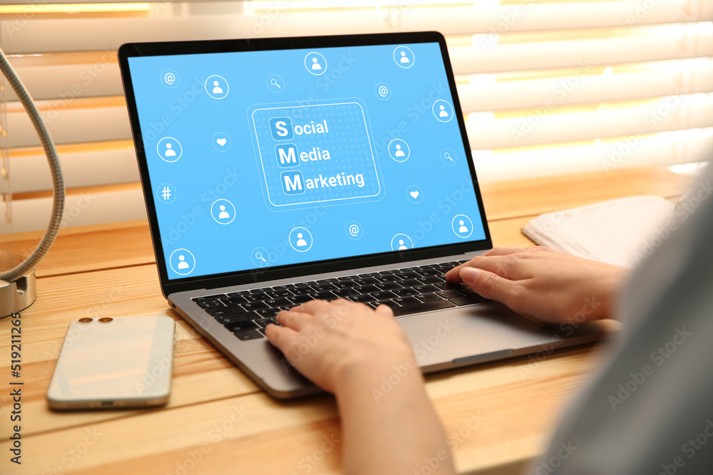 SMM (Social Media Marketing) concept. Woman working with modern laptop at wooden table, closeup SMM (Social Media Marketing) concept. Woman working with modern laptop at wooden table, closeup