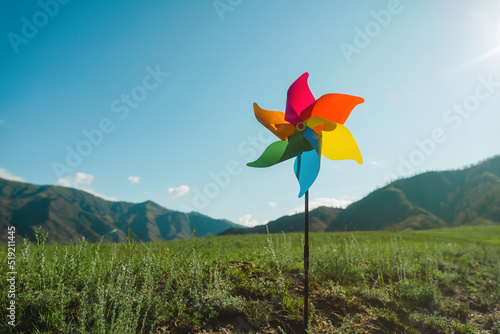 Symbol of clean green energy, pinwheel ibackground of the sky and a green landscape photo